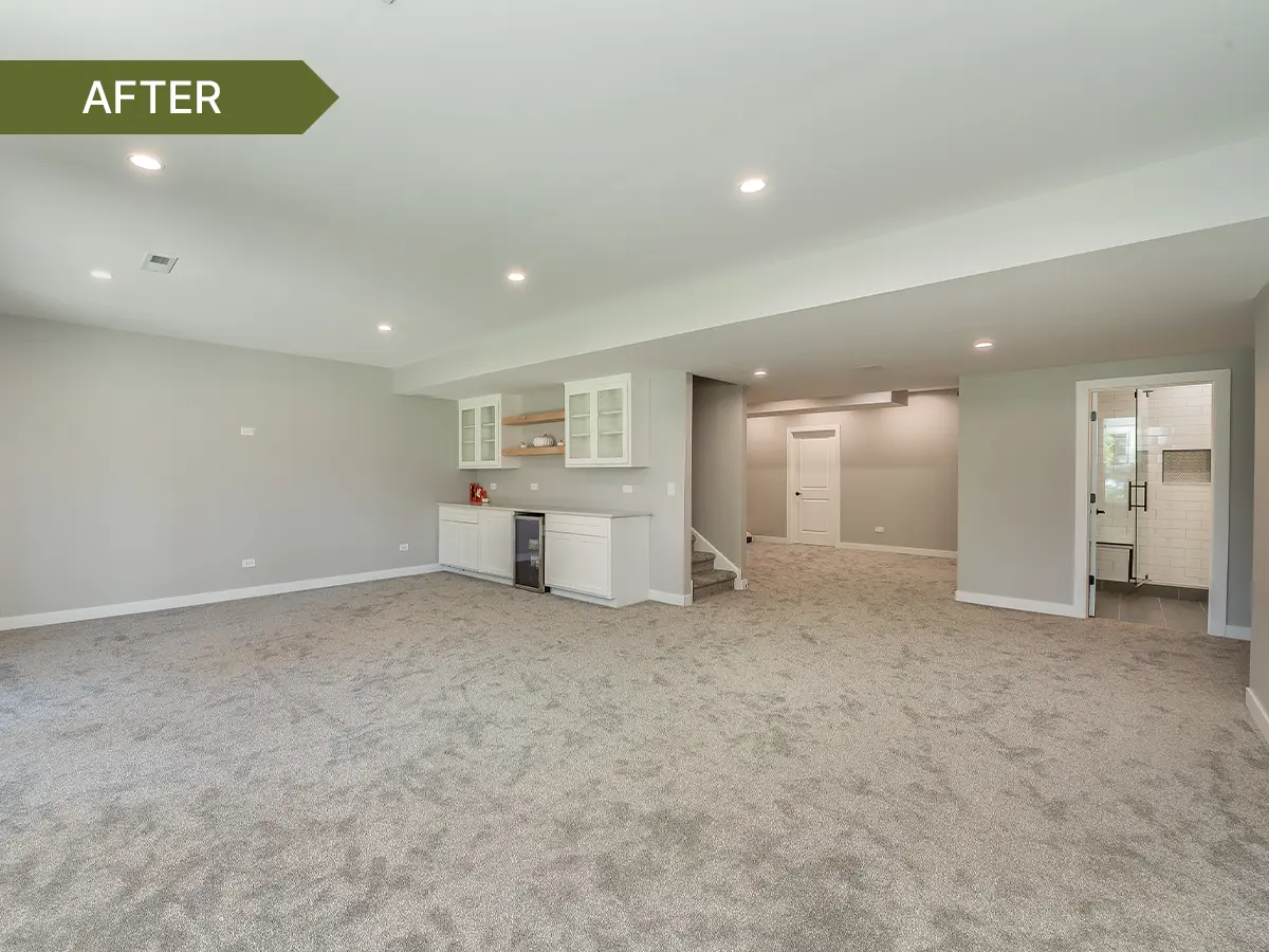 Finished basement with recessed lighting, gray walls, carpeted floors, built-in white cabinets with a small beverage fridge, stair access, and a bathroom with a tiled shower.