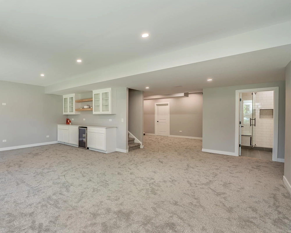 Spacious finished basement with carpet, wet bar, and bathroom access.