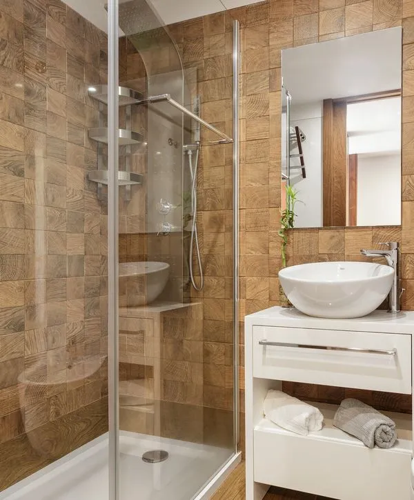 Modern walk-in shower featuring brown wood-look textured wall tiles and a white vanity sink in a Yorkville, IL bathroom remodeling project.