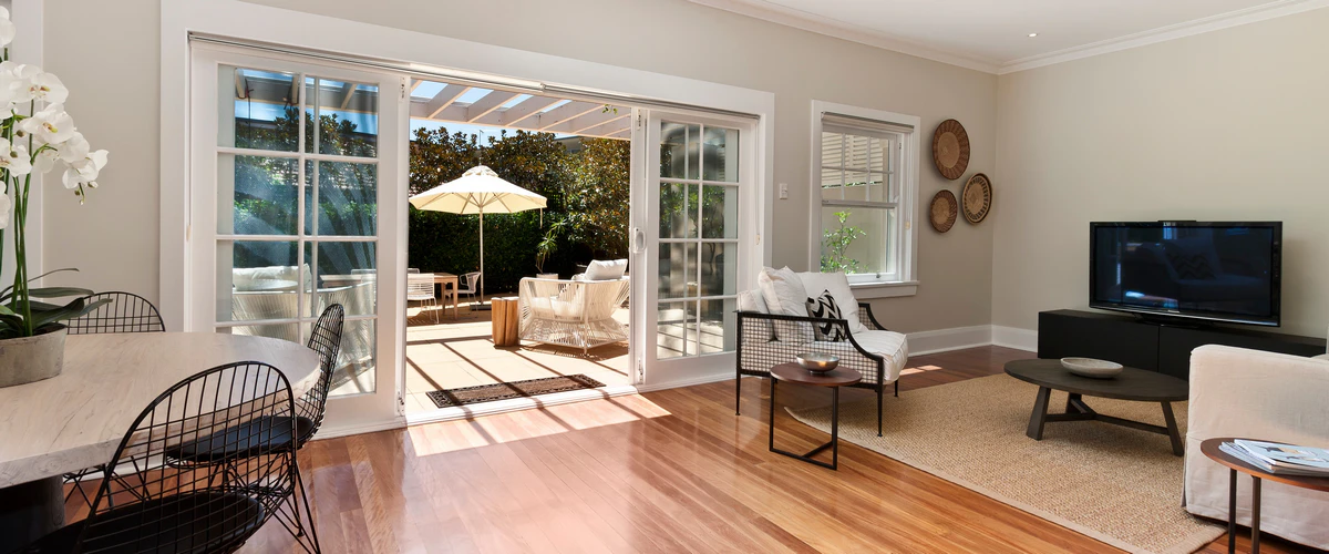 An open-concept living and dining area with sliding glass doors leading to an outdoor patio, showcasing a high-end home addition.