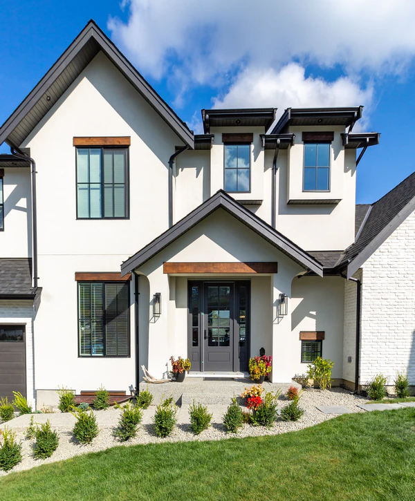 A modern white stucco custom home exterior featuring black window frames and wooden accents in Yorkville, IL.