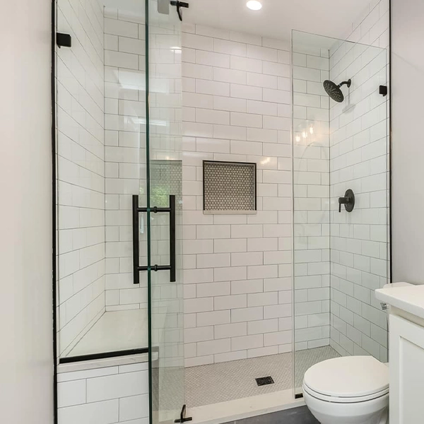 Glass walk-in shower with white subway tile and built-in niche.