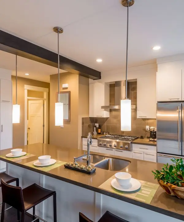 Modern kitchen remodeling in Oswego, IL, featuring a large brown island with pendant lighting and stainless steel appliances.