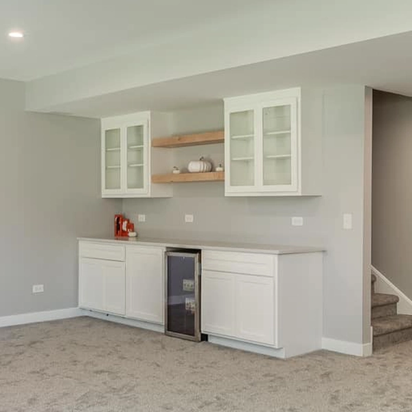 Basement wet bar with white cabinets and beverage fridge.