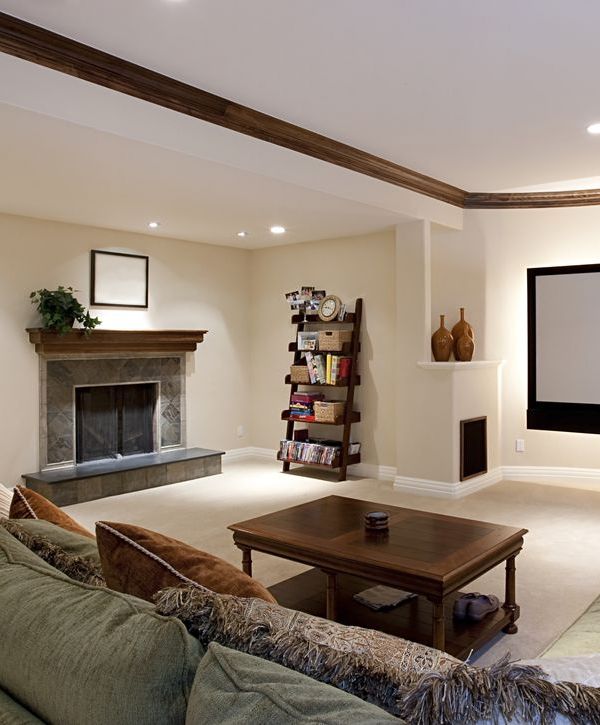 A spacious living area featuring professional basement remodeling in Yorkville, IL, with a stone fireplace, wood mantle, and built-in shelving.