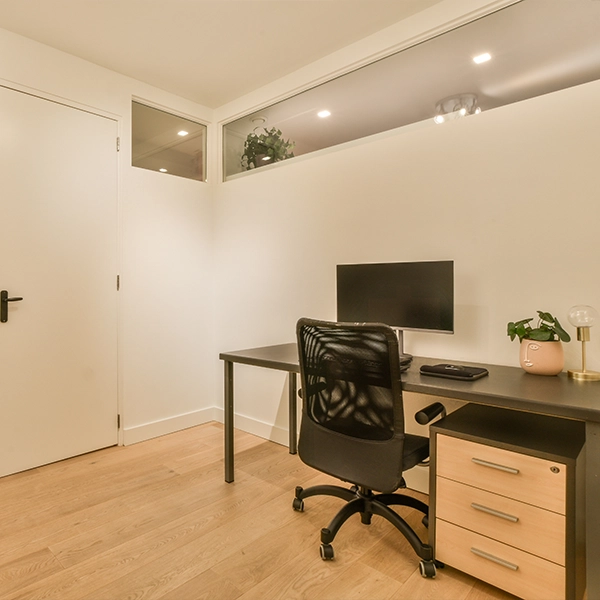 Minimalist home office with desk, monitor, and black chair.