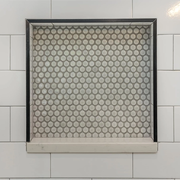 Shower niche with penny tile detail and metal trim frame.