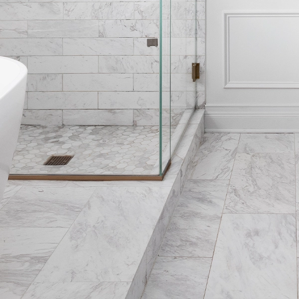 Marble-look tile shower with glass enclosure and hex tile floor.